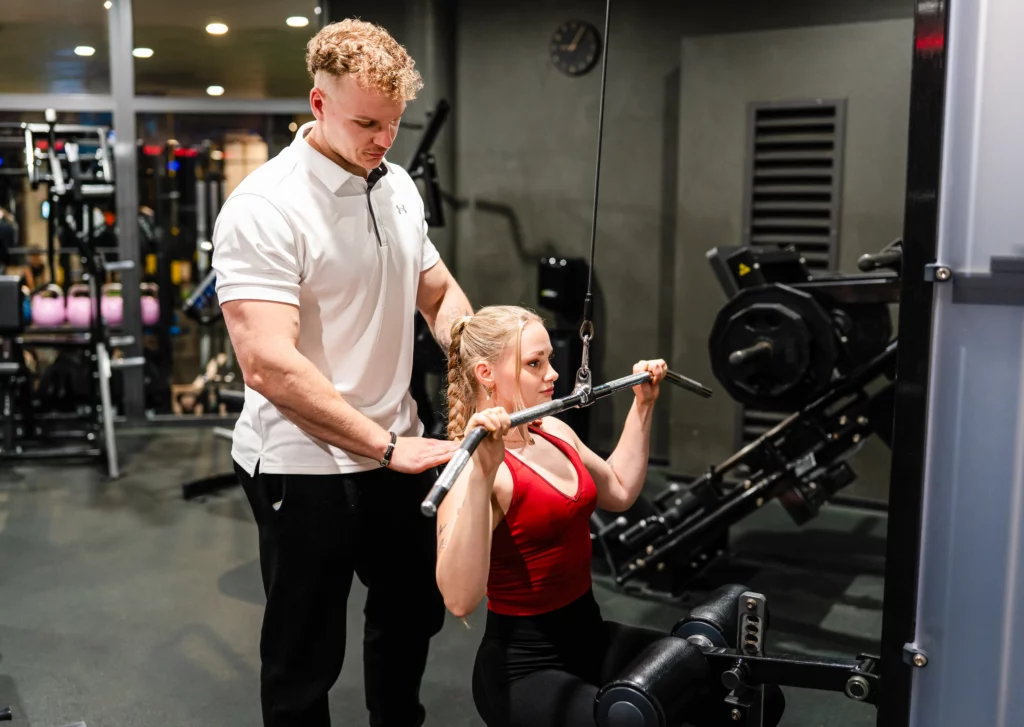 Jonas Buchner leistet Hilfestellung bei einer Kundin die Ihren Rücken trainiert.