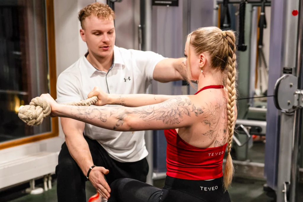 Jonas Buchner leistet Hilfestellung bei einem Personal Training in einem Fitnessstudio.